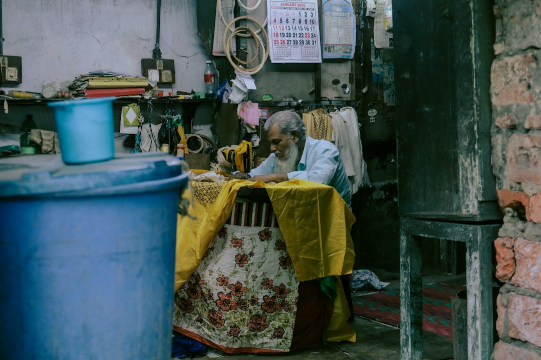 A man sewing at a table in a small workshop
